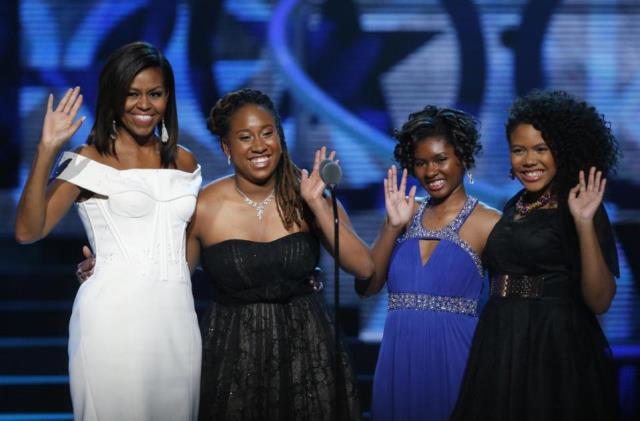 First Lady Michelle Obama, left, waves while standing on stage with Making A Difference award winners, from left, Kaya Thomas, Chental-Song Bembry and Gabrielle Jordan during a taping of the Black Girls Rock award ceremony at the New Jersey Performing Arts Center, Saturday, March 28, 2015, in Newark. (AP Photo/Julio Cortez)