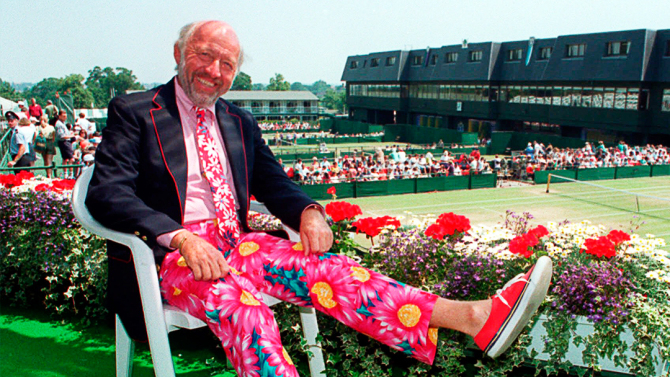 NBC tennis commentator Bud Collins displays a pair of brightly-colored trousers as he sits overlooking the outside courts at Wimbledon, England, June 30, 1993. Collins, participating in his 22nd Wimbledon, will choose from four pairs of trousers, which he will wear on the air, for the Men's and Ladies' Singles finals . (AP photo/Gill Allen)