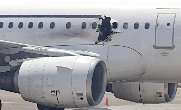 In this Tuesday, Feb. 2, 2016 photo, a hole is photographed in a plane operated by Daallo Airlines as it sits on the runway of the airport in Mogadishu, Somalia. A gaping hole in the commercial airliner forced it to make an emergency landing at Mogadishu's international airport late Tuesday, officials and witnesses said. (AP Photo)